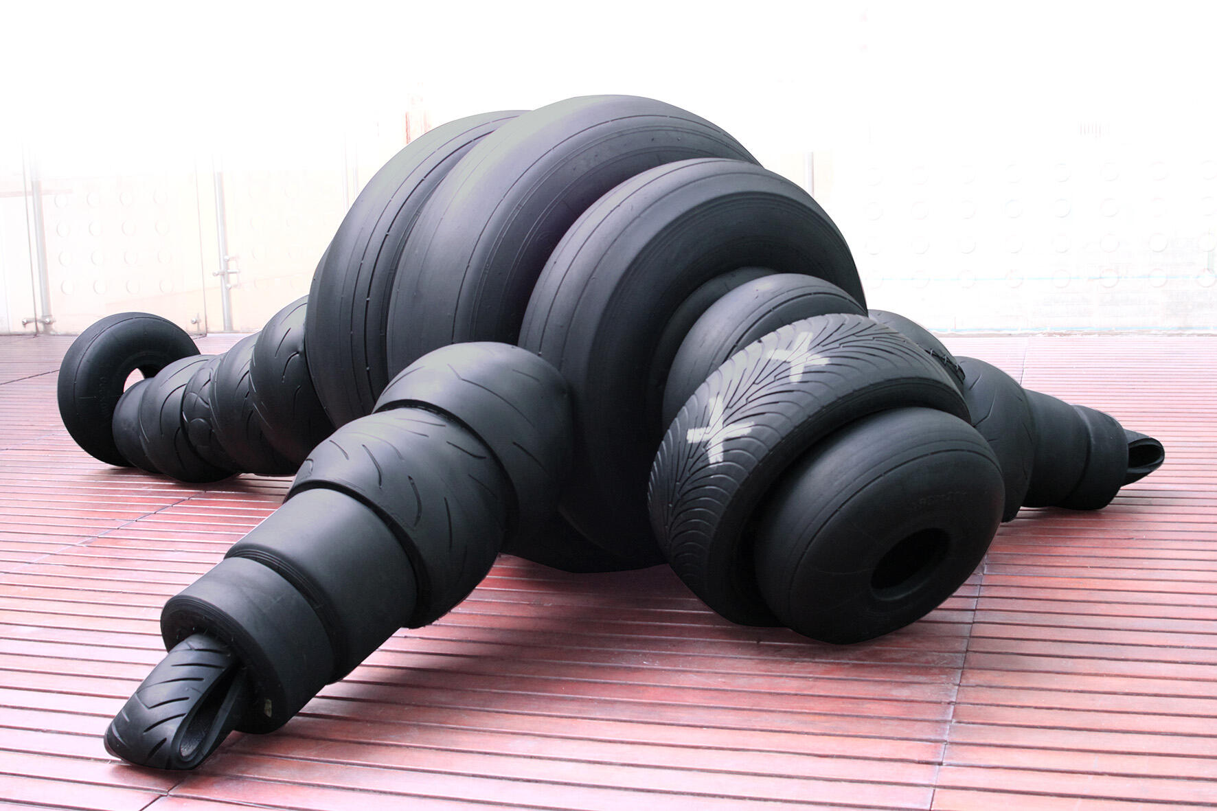 Black sculptural form resembling stacked tires on a white background.