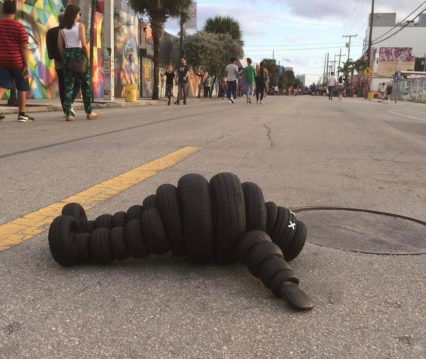 Black sculptural form resembling stacked tires on a white background.
